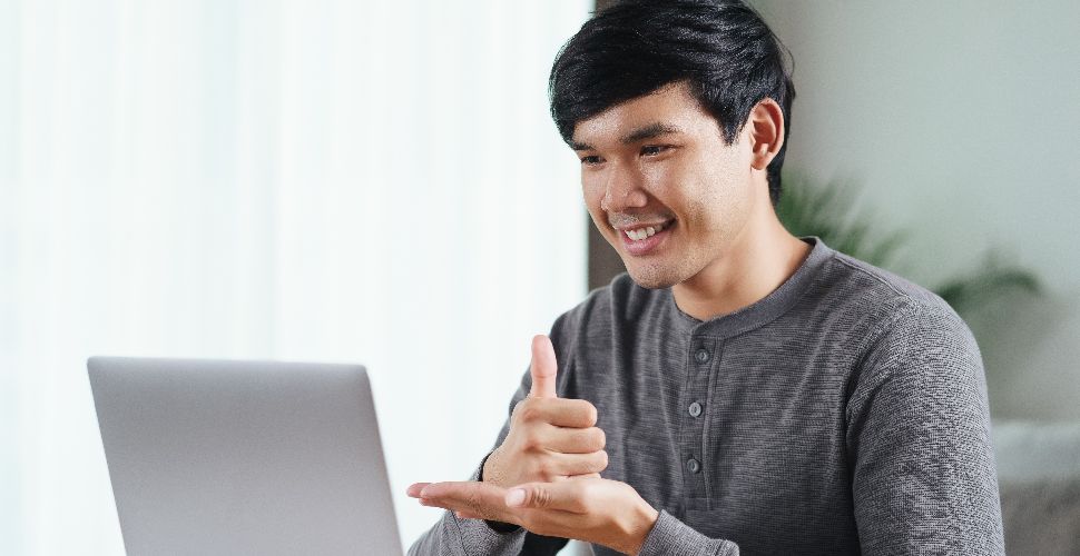 Man-giving-thumbs-up-to-people-on-laptop-screen