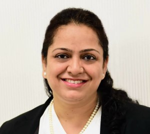 Portrait of a person smiling, wearing a pearl necklace and blazer.