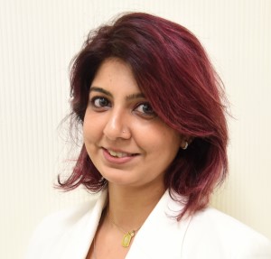 Person with red hair smiling, wearing a white jacket.