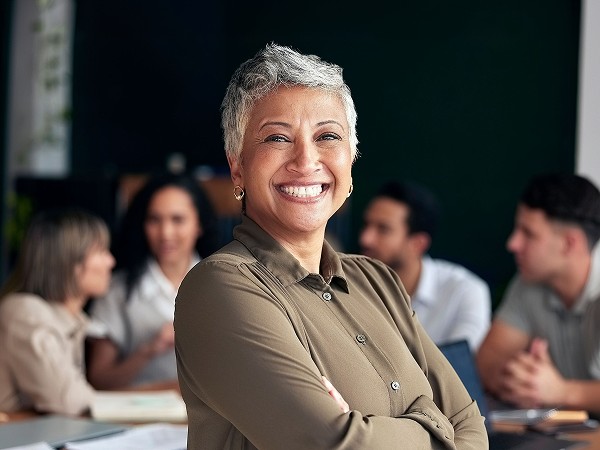 A lady in an office attire smiling with a blue gradient background.