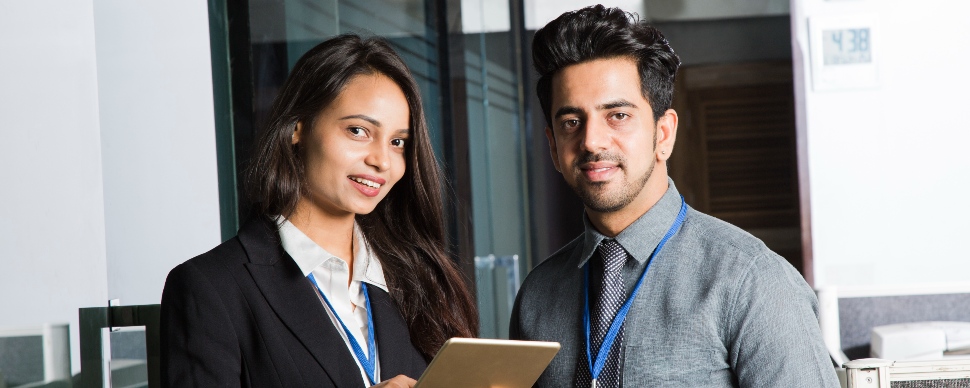 Two business professionals, a man and a woman, smiling, in an office setting.