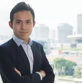 Person in a suit with arms crossed, city skyline in the background.