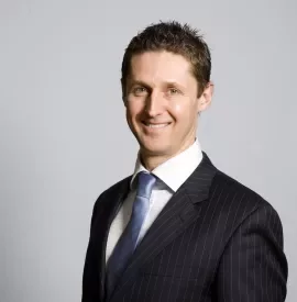 Person in a suit and tie smiling at the camera.