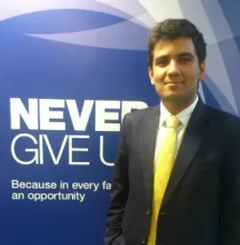 Person in a suit standing beside a motivational sign saying 'Never Give Up'.