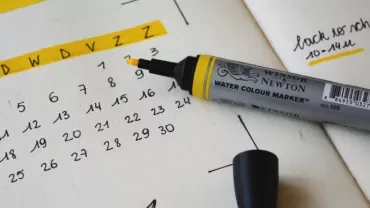 Open calendar with yellow highlighter on paper.