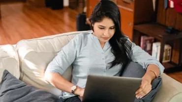 Person sitting on a couch using a laptop.