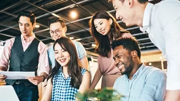 Group of people collaborating around a laptop in an office.