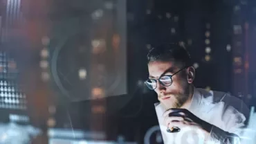Person analyzing data on computer screens with graphs and charts.