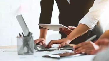 People collaborating with laptops and tablets in a modern office.