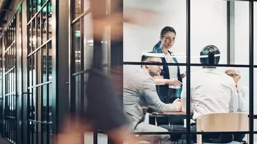 Group of people having a meeting in a glass-walled office.