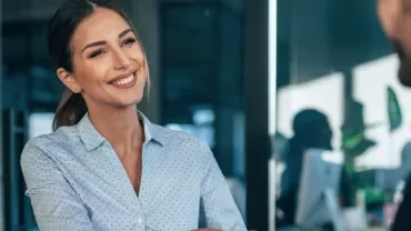Person smiling while shaking hands in an office environment.