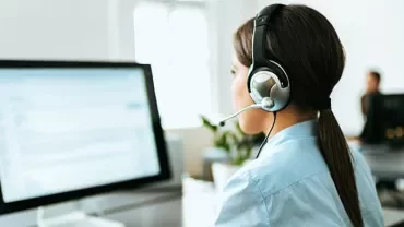Person wearing headset working on a computer in an office.