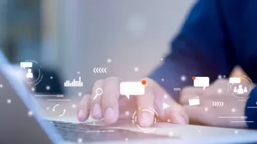 Hands typing on a laptop with floating digital icons.