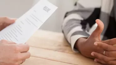 Two people seated at a table, one holding a resume.