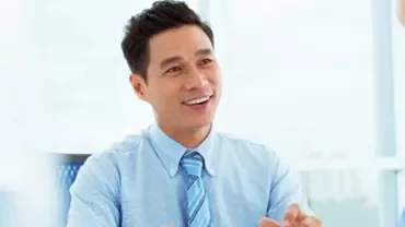 Person in a blue shirt smiling during a conversation in an office.