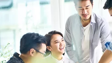 Smiling coworkers having a discussion around a table in a bright office.