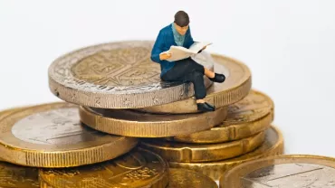 figurine of a man sitting on gold coins