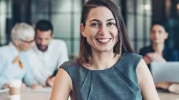 Person smiling at the camera in a modern office setting.