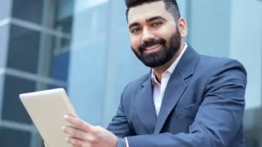 Person in a suit using a tablet outside a building.