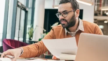 One male professional going through documents at a work desk