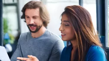 A man and woman review a document, discussing strategies for retaining top talent through career growth opportunities.