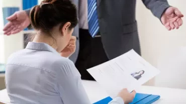 Person in a meeting holding a resume, looking down.