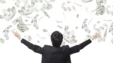 Person in a suit with arms raised, as dollar bills fall from above against a white background.