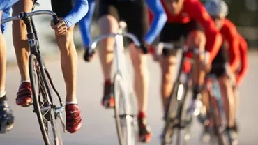 Cyclists in a race on a sunny day, wearing blue and red outfits.