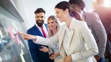 Group of people interacting with a digital screen in a modern office.