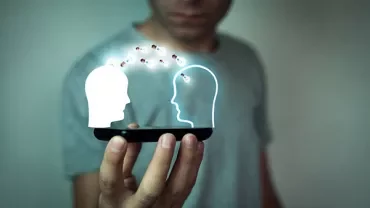 Person holding a smartphone projecting two glowing head outlines exchanging data.
