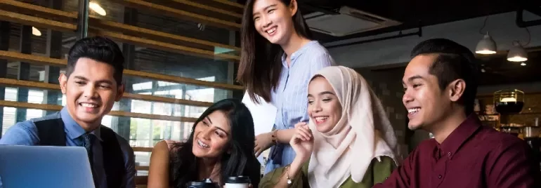 Group of people smiling and looking at a laptop in an office.