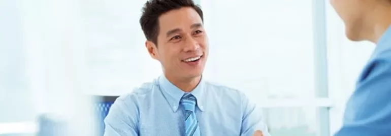 Person in a blue shirt smiling during a conversation in an office.