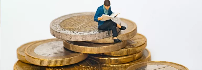 figurine of a man sitting on gold coins