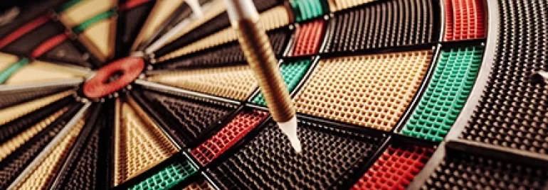 Close-up of darts on a colorful dartboard.