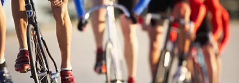 Cyclists in a race on a sunny day, wearing blue and red outfits.