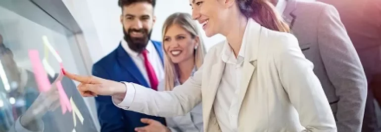 Group of people interacting with a digital screen in a modern office.