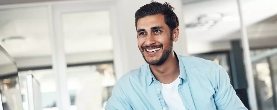 Person smiling in an office setting with glass walls in the background.