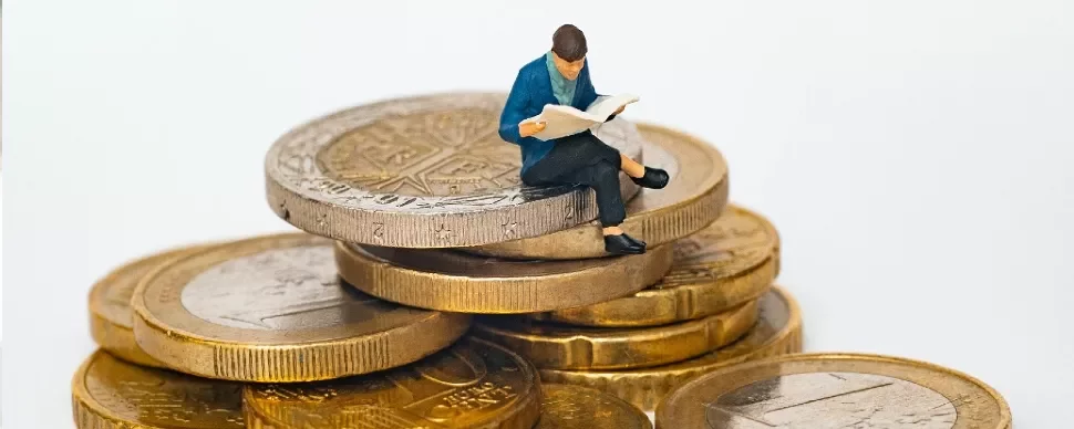 Figure reading a newspaper while sitting on a stack of coins.