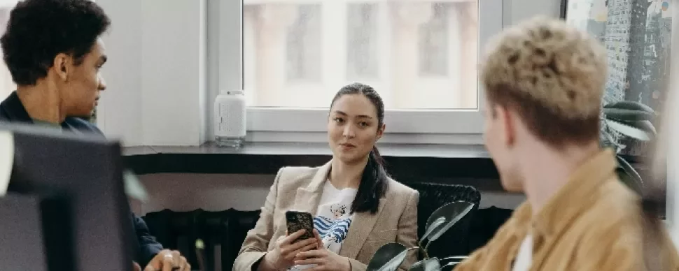Three people having a discussion in an office.