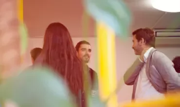 Group of people engaged in conversation in a brightly lit room.