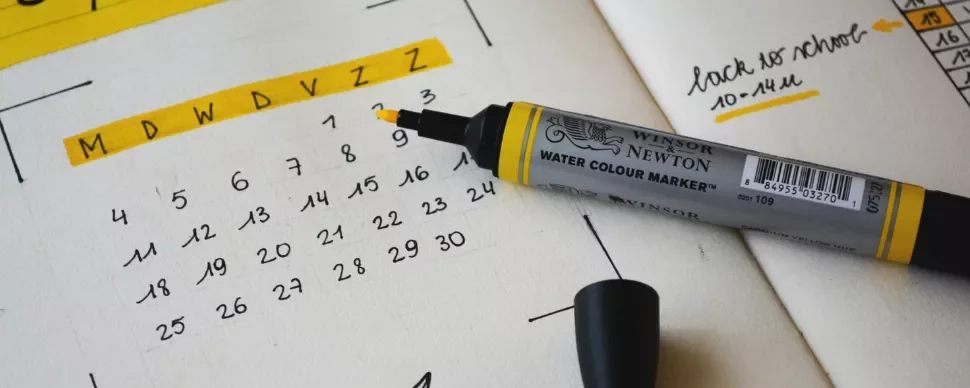 Open calendar with yellow highlighter on paper.