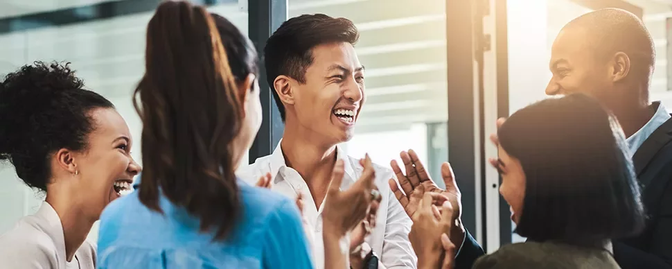 Group of people laughing and clapping in a bright office.