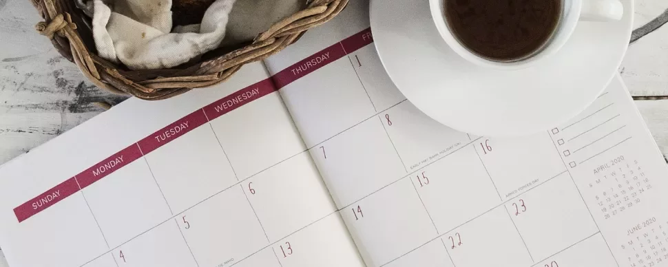 Open calendar with coffee cup and bread basket.