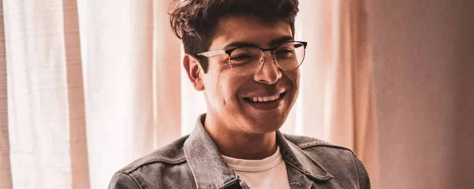 Person smiling while wearing glasses and a denim jacket.