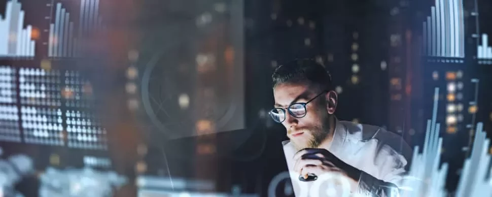 Person analyzing data on computer screens with graphs and charts.