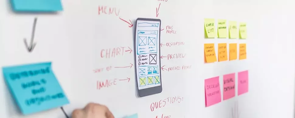 Mobile app design sketch on a whiteboard with sticky notes and diagrams.