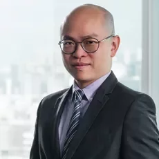 Person in a suit and tie standing in front of a window with city view.