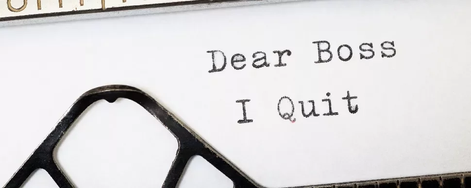 Typed words on paper saying 'Dear Boss, I Quit' with typewriter keys visible.