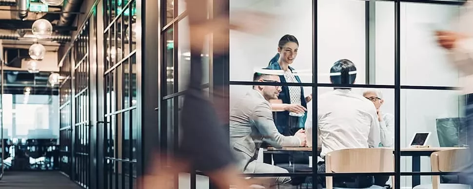 Group of people having a meeting in a glass-walled office.