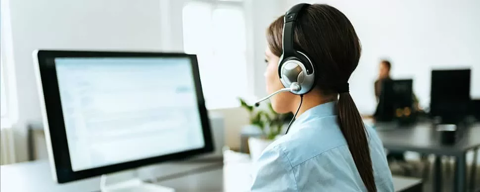 Person wearing headset working on a computer in an office.